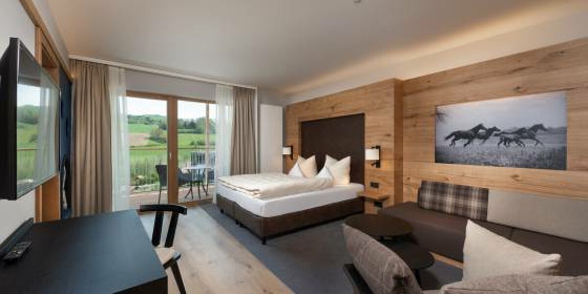 Freundliches und modernes Hotelzimmer mit Bett, Sofa und Schreibtisch