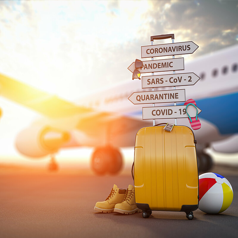 Gelber Reise-Koffer steht mit vielen Schildern, Schuhen und Ball vor Flugzeug