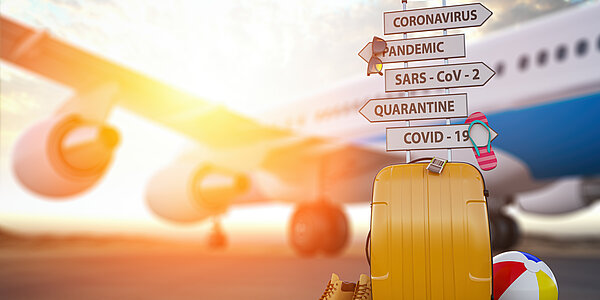 Gelber Reise-Koffer steht mit vielen Schildern, Schuhen und Ball vor Flugzeug