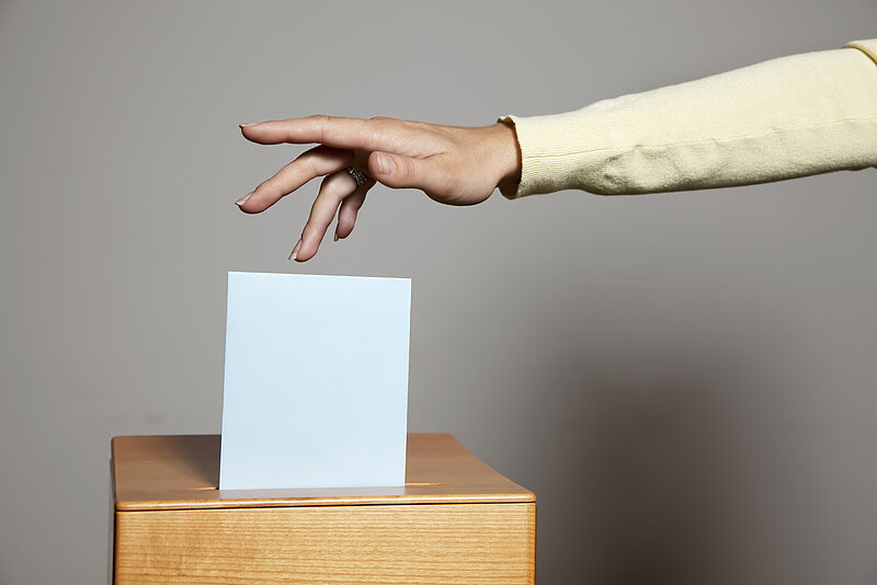 Stimme wird in Wahlurne geworfen.