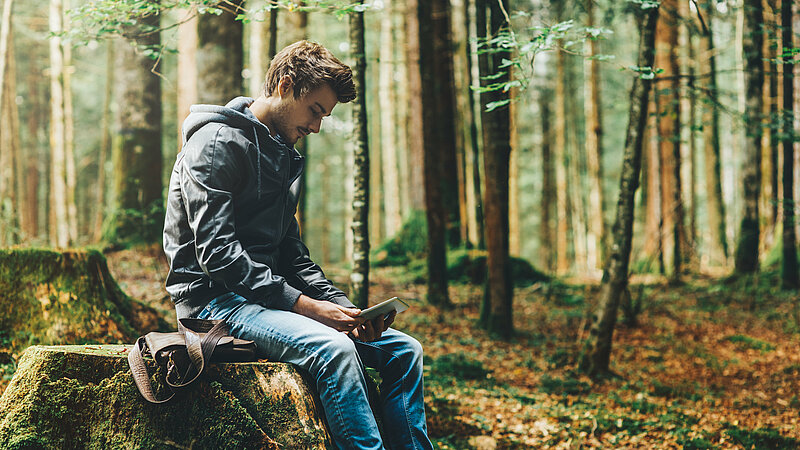 Wanderer mit Smartphone im Wald