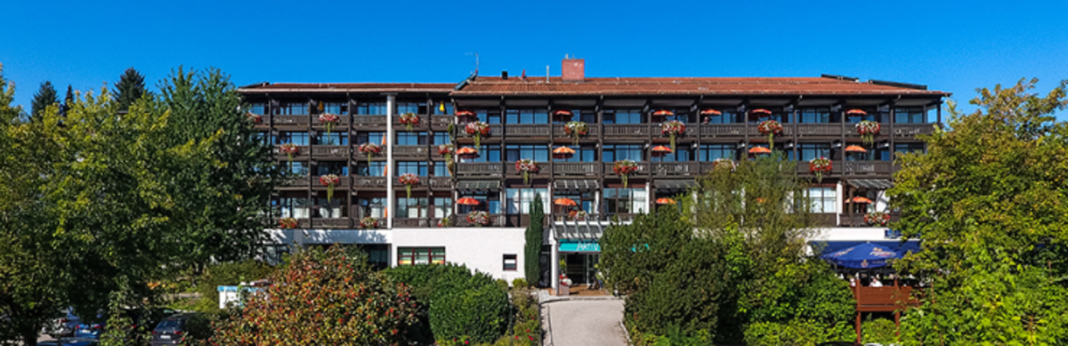 Großes Hotel mit vielen Zimmern und Balkonen vor blauem Himmel