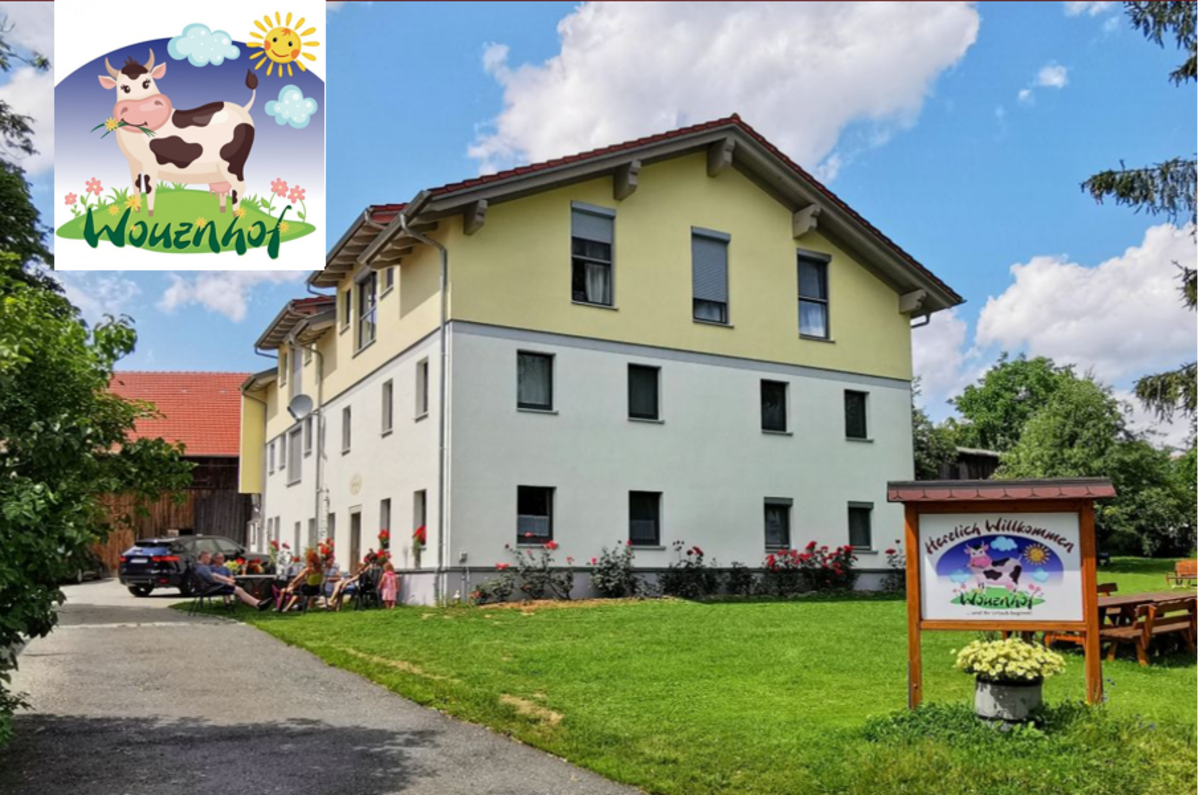 Großes Bauernhaus im Grünen, Schild mit Logo im Vorgarten