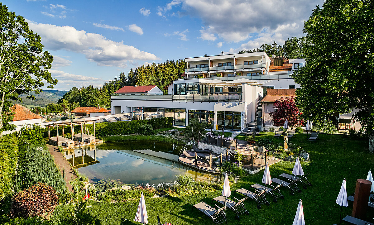 Rückansicht des Hotels mit Balkonen, Schwimmteich und Liegewiese