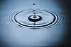 Wassertropfen, der Kreise in der Wasserfläche verursacht.