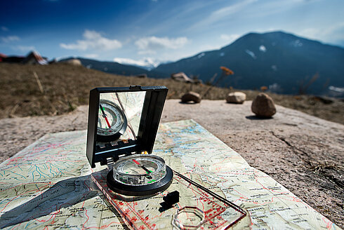 Kompass und Landkarten vor Bergkulisse 